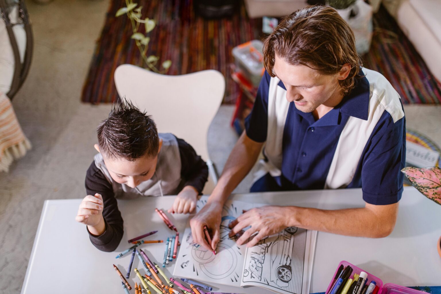 A father and son enjoy coloring together, fostering creativity and bonding in a cozy indoor setting.